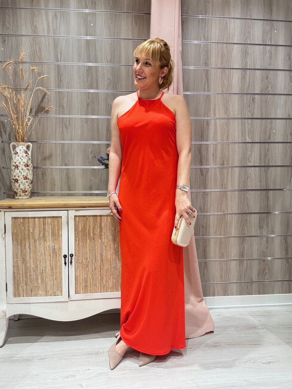 Vestido largo satinado en tono naranja intenso con tirantes finos y escote halter.