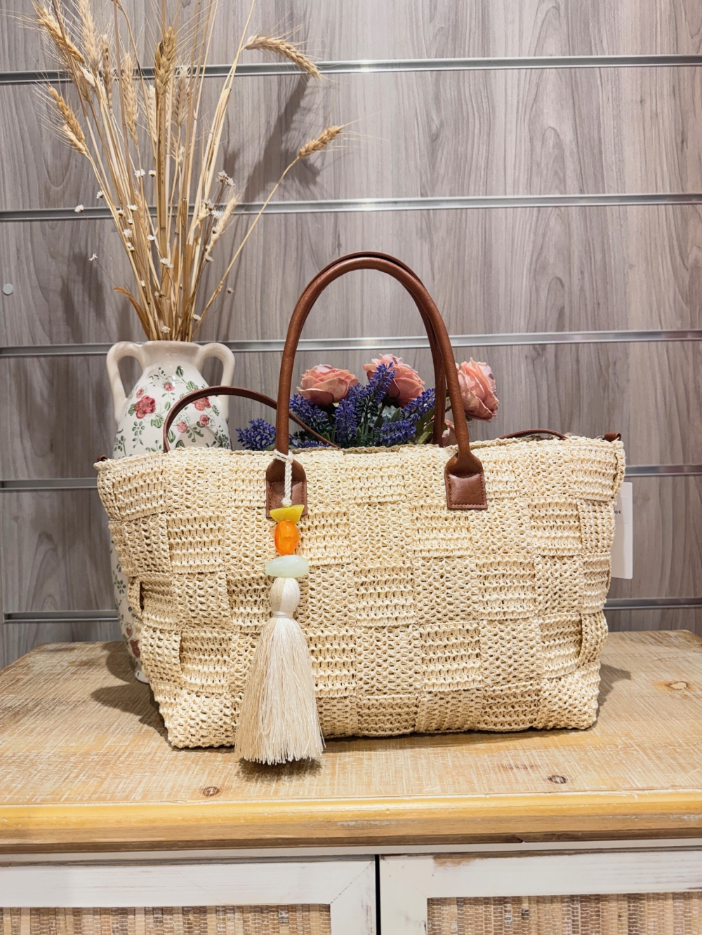 Bolso de rafia en tono natural con asas efecto cuero y borla decorativa de cuentas y fleco.