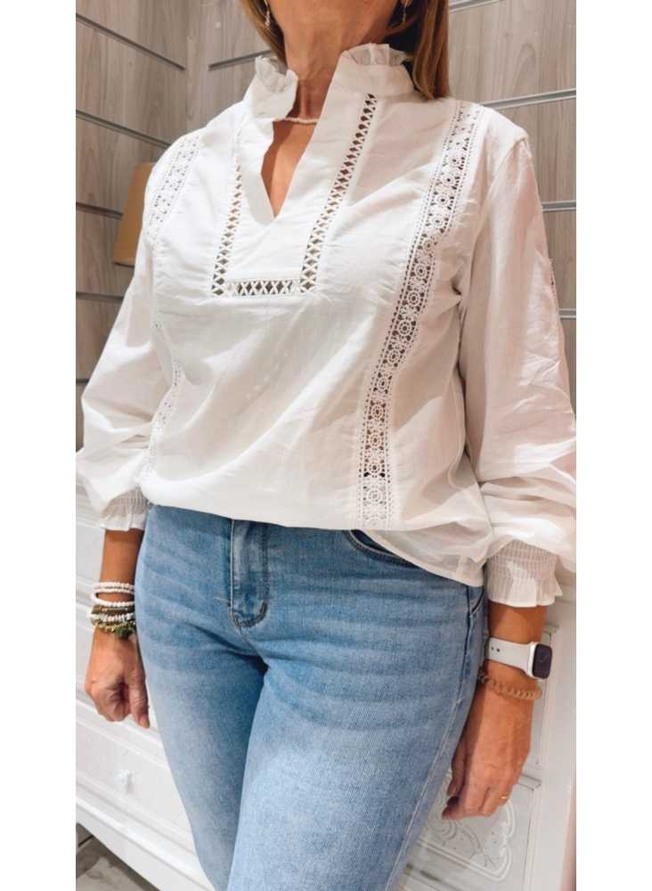Camisa blanca con cuello fruncido y detalles de encaje calado, ideal para un look romántico y femenino. Camisa blanca con cuello fruncido y detalles de encaje calado, ideal para un look romántico y femenino.